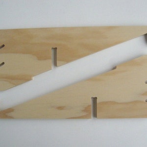 May include: Two wooden pieces of plywood with cutouts, forming a stand for a laptop or tablet. The stand is made of light brown wood.