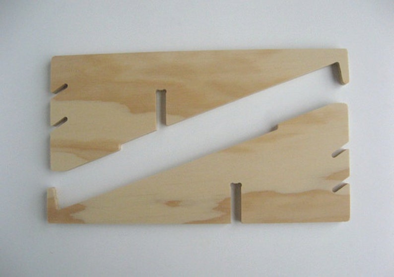May include: Two wooden pieces of plywood with cutouts, forming a stand for a laptop or tablet. The stand is made of light brown wood.