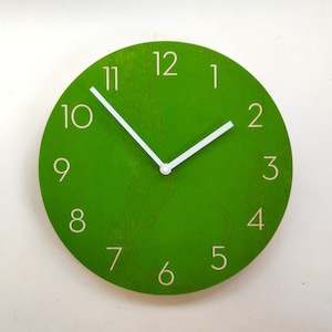 May include: A green round clock with white hands and white numbers. The clock face has a wood grain texture.