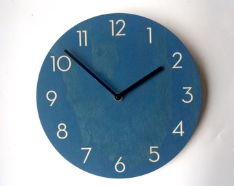 May include: A blue round clock with white numbers and black hands. The clock face has a distressed look.