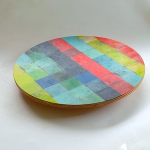Könnte beinhalten: Ein rundes Holztablett mit einem bunten geometrischen Muster. Das Muster zeigt Streifen in Rot, Grün, Blau und Gelb.