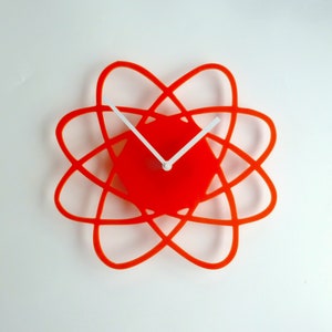 May include: Orange and white modern wall clock with a unique atomic design. The clock has white hands and a red face.