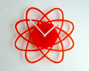 May include: Orange and white modern wall clock with a unique atomic design. The clock has white hands and a red face.