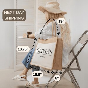 A woman sitting in a chair, wearing a straw hat and carrying a large bag with the word "OLIVIA" printed on it.