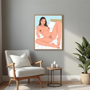 May include: A framed art print featuring a nude illustration of a person reclining on a bed. The artwork depicts a person with brown hair and red lips, set against a light blue background. The print is displayed in a room with a chair, side table, and a potted plant.