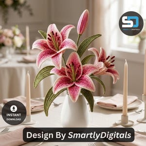 May include: A crochet lily flower arrangement in a white vase, featuring pink and white petals with dark stamens and green leaves. The flowers are displayed on a table with taper candles and napkins. The image includes the text Design By SmartlyDigitals.