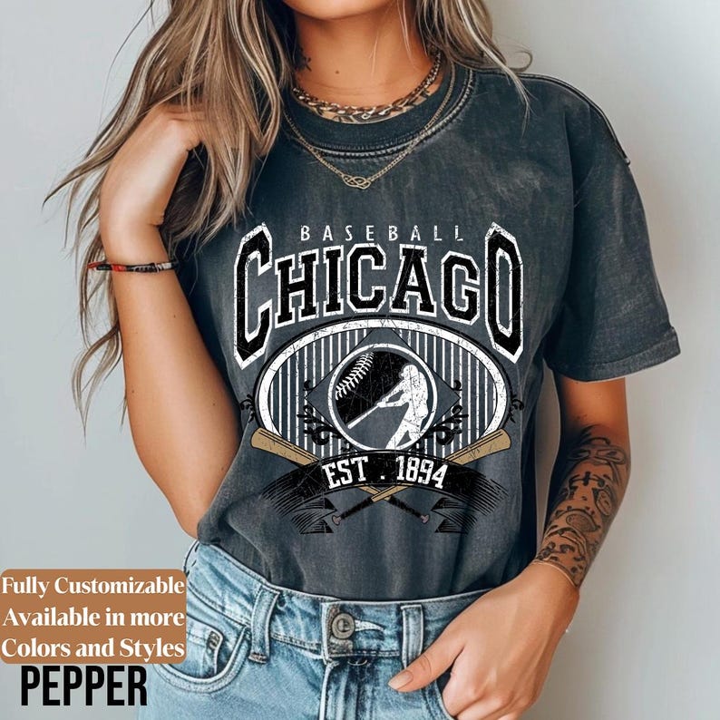 May include: Dark gray baseball t-shirt with a vintage Chicago design. The design includes the word "Chicago" in a bold font, a baseball, a batter silhouette, and the year "1894". The shirt is a classic fit.