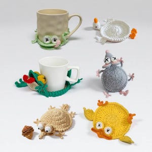 Peut inclure: Une collection de dessous de verre et figurines en crochet faits main comprenant un mug beige avec un dessous de verre grenouille vert, un mug blanc avec un dessous de verre vert et rouge, un dessous de verre canard blanc, une souris grise, un escargot beige et un dessous de verre canard jaune.