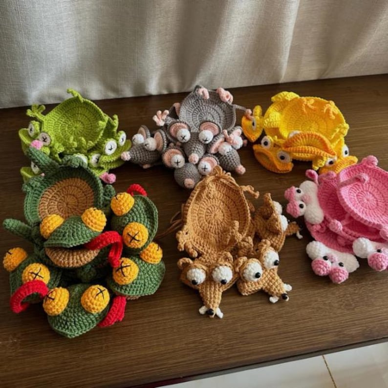 Peut inclure: Une collection de dessous de verre au crochet repr&eacute;sentant divers animaux, notamment des grenouilles vertes, des souris grises, des crabes jaunes, des &eacute;cureuils marron et des cr&eacute;atures roses. Chaque pi&egrave;ce a une base circulaire avec des d&eacute;tails.