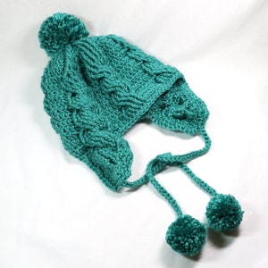 May include: Teal blue crocheted hat with ear flaps and pom poms on the top and the ends of the ties.