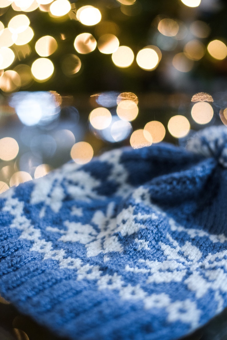 Pu&ograve; includere: Un cappello blu lavorato a maglia con un motivo a fiocco di neve bianco. Il cappello &egrave; morbido e confortevole, perfetto per l'inverno.