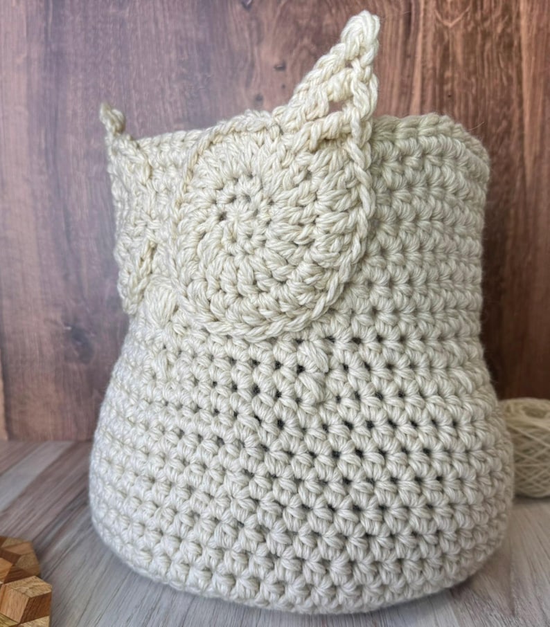 May include: A crocheted owl-shaped basket made of beige yarn. The basket has a round body and two large ears.