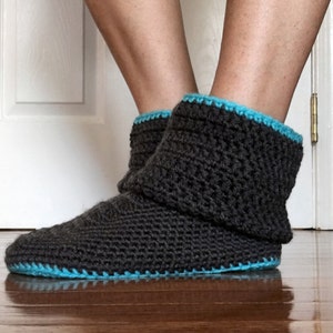 May include: Gray crocheted slipper boots with a blue trim. The boots are folded down at the top.