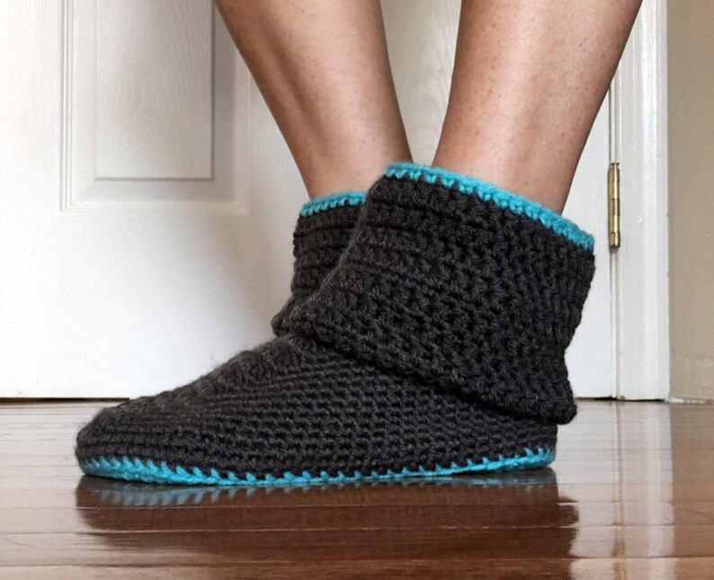 May include: Gray crocheted slipper boots with a blue trim. The boots are folded down at the top.