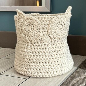 May include: A crocheted owl-shaped basket in a cream color. The basket is made of yarn and has a textured surface.
