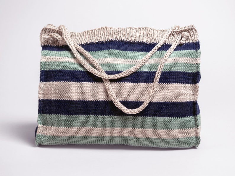 May include: A striped knitted tote bag with beige, blue, and green stripes. The bag has a thick, beige knitted strap.