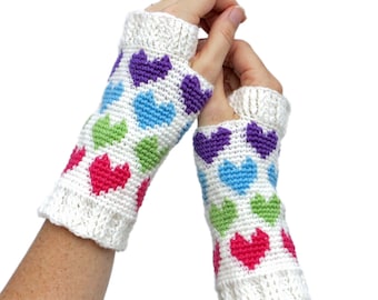 May include: A pair of white crocheted fingerless gloves with a colorful heart pattern. The hearts are in shades of pink, purple, green, and blue.