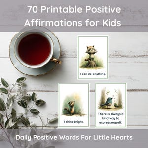Könnte beinhalten: Draufsicht auf einen Tisch mit einer Teetasse, Zweigen und drei Karten mit Illustrationen und positiven Affirmationen. Die Karten lauten: „Ich kann alles schaffen“, „Ich strahle hell“ und „Es gibt immer eine freundliche Art, mich auszudrücken“.