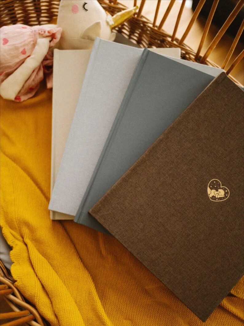 Babyalbum erstes Jahr mit neutralem Leineneinband und personalisierbarer ‚Über mich‘-Seite – Babyhände halten Fotos zum Einkleben. Hochwertiges Erinnerungsbuch mit handgezeichneten Aquarellillustrationen, Platz für Babyfotos, Meilensteine, Entwicklung und Familienmomente. Ideal als Geschenk zur Geburt, Taufe oder Babyparty für neue Eltern. Premium Babybuch zum Festhalten der wichtigsten Erinnerungen im ersten Lebensjahr