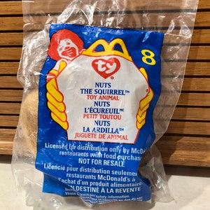 May include: A blue and yellow McDonald's Happy Meal bag with a Ty Beanie Baby Squirrel inside. The bag has the words "Nuts the Squirrel" and "Toy Animal" printed on it. The bag also has the number 8 printed on it.