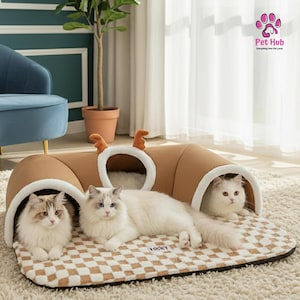Puede incluir: Una cama para gatos marrón con diseño de túnel y cuernos de reno, con tres gatos descansando sobre ella. La cama tiene un patrón de cuadros y un interior blanco. El logotipo de Pet Hub es visible en la esquina superior derecha.