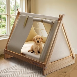 Puede incluir: Cama para perros en forma de A con una cubierta de lona beige claro y un marco de madera. Un cachorro de golden retriever está sentado dentro de la cama. La cama tiene el texto "PET PEACE".