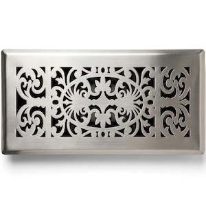 May include: A rectangular floor register with a brushed silver metal finish. The surface features a laser-cut pattern consisting of a central oval motif surrounded by intricate scrolling filigree designs, revealing a dark interior through the cutouts.