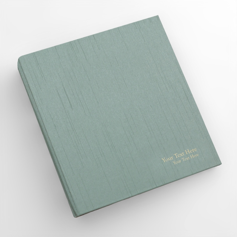 May include: A teal green binder with a textured linen cover. The text "Your Text Here" is printed in gold on the front cover.