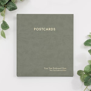 May include: A green, textured, square-shaped postcard album with the word "POSTCARDS" embossed in gold lettering. The text "Your Text Embossed Here" is also embossed in gold lettering on the bottom of the album.