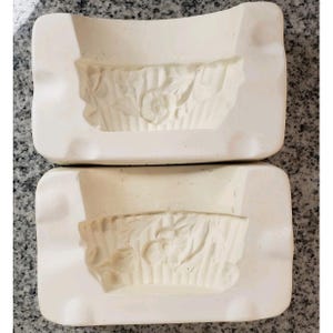 May include: A set of three ceramic mugs with a speckled, matte finish. The mugs are in shades of cream, light gray, and dark gray. Each mug has a simple, minimalist design and a rounded handle.