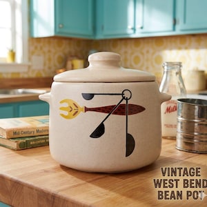 May include: A vintage West Bend bean pot with a lid, featuring a speckled beige finish and a graphic of a fork and spoons in yellow, brown, and black. The pot has two side handles and the text "VINTAGE WEST BEND BEAN POT".