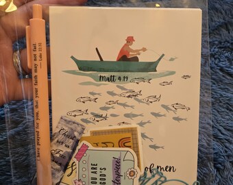 May include: A clear plastic bag containing a greeting card, stickers, and a pen. The card features a man fishing from a boat with the text "Matt 4.19". The pen is peach-colored with text. Stickers include inspirational quotes.