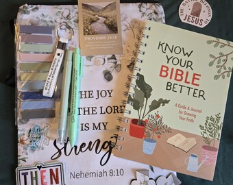 May include: A spiral-bound journal titled Know Your Bible Better, a floral tote bag with the text The Joy of the Lord is My Strength, a pack of sticky tabs, two pens, a keychain, stickers, and small cross-shaped cutouts with religious text.