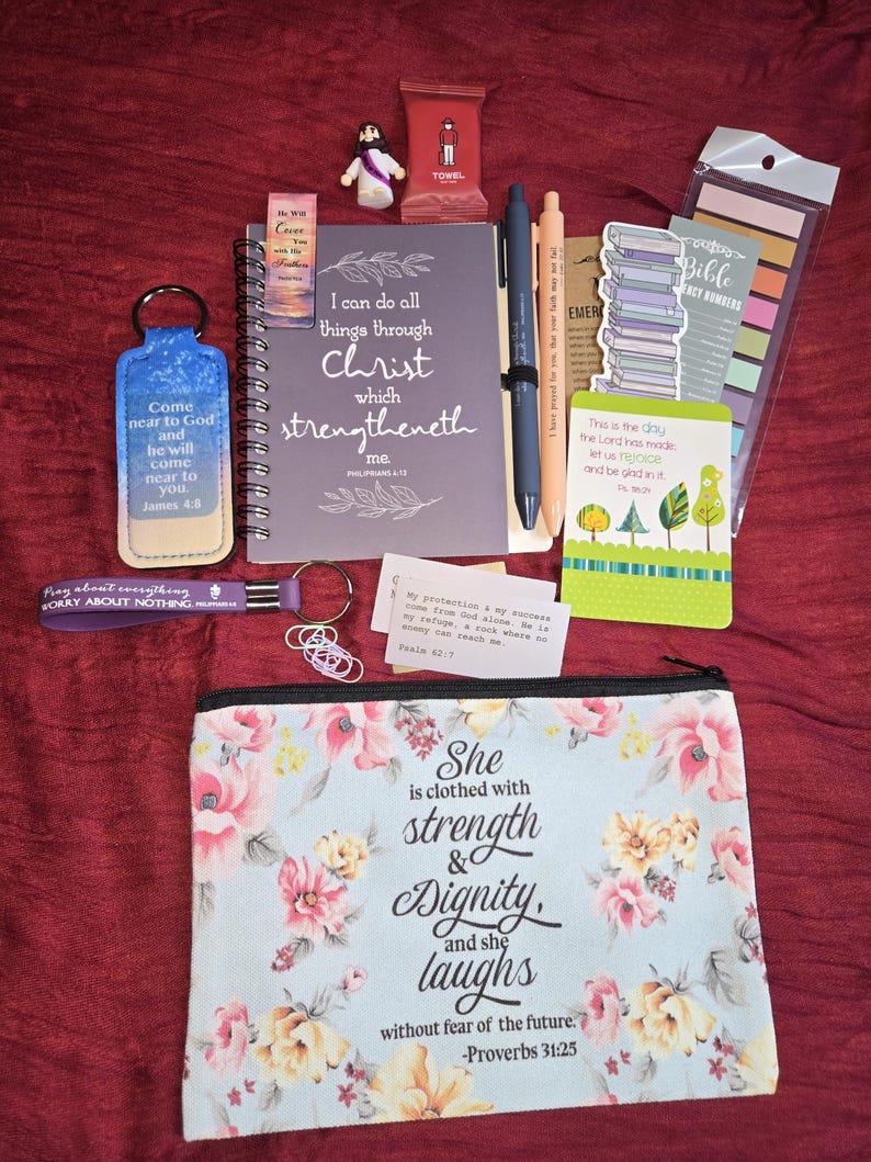 May include: A collection of religious stationery and accessories including a spiral-bound notebook with the text I can do all things through Christ, a floral zippered pouch with Proverbs 31:25, two pens, keychains, bookmarks, and small cards with scripture.