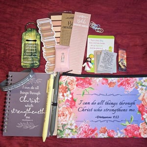 May include: A collection of religious stationery items including a spiral-bound notebook, a floral zippered pouch, pens, bookmarks, and small cards. The items feature the text I can do all things through Christ who strengthens me and Philippians 4:13.