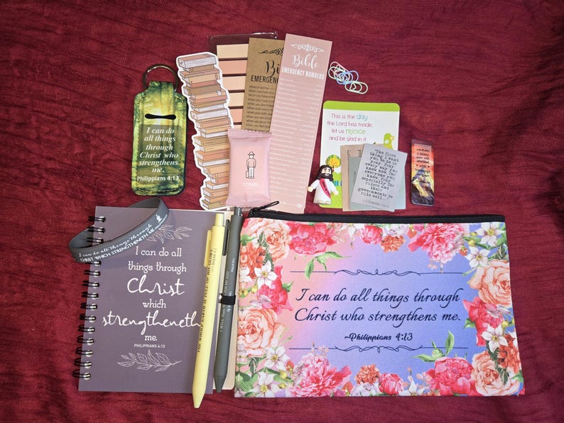 May include: A collection of religious stationery items including a spiral-bound notebook, a floral zippered pouch, pens, bookmarks, and small cards. The items feature the text I can do all things through Christ who strengthens me and Philippians 4:13.