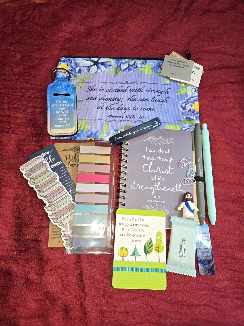 May include: A collection of religious stationery items including a floral zippered pouch with Proverbs 31:25-26, a spiral notebook with Philippians 4:13, a chapstick holder, colorful sticky tabs, pens, a small Jesus figurine, and various scripture cards.