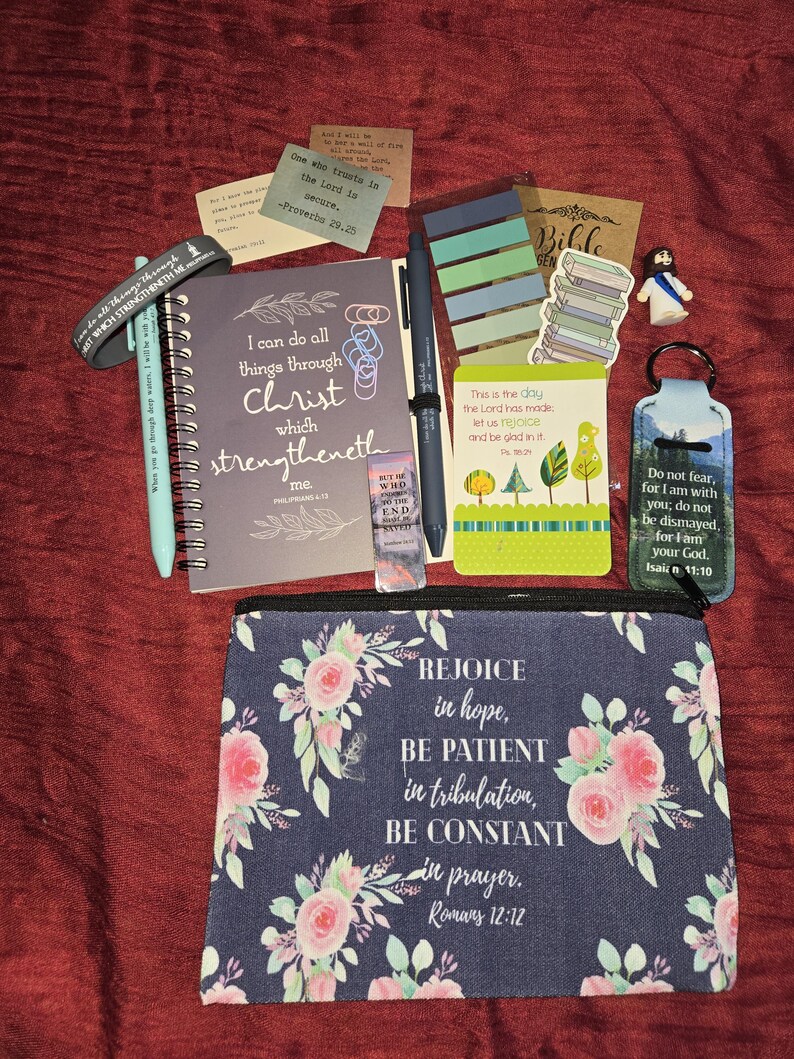 May include: A collection of religious stationery items including a spiral-bound notebook with the text I can do all things through Christ which strengtheneth me, a floral zippered pouch with Romans 12:12, pens, bookmarks, stickers, and a keychain.