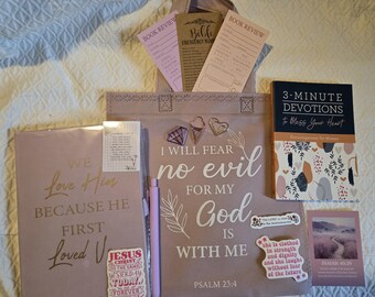 May include: A mauve tote bag printed with the text I WILL FEAR no evil FOR MY God IS WITH ME PSALM 23:4, accompanied by a devotional book, a journal with gold text, three bookmarks, a light purple pen, three metal paperclips, and stickers.