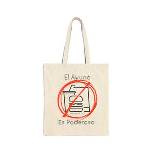 May include: A beige canvas tote bag with black text and a red and black graphic. The graphic depicts a burger and drink crossed out with a red circle and line. The text reads "El Ayuno Es Poderoso" and "Mateo 4:1-11".