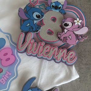 May include: A white t-shirt with a pink, blue and silver glitter appliqu&eacute; featuring the number 8, the name "Vivienne", and three Stitch characters. The Stitch characters are blue, pink and blue with pink hearts for eyes.