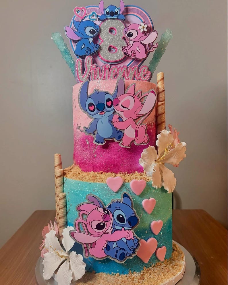 May include: A two-tiered cake decorated with a blue and pink Stitch and Angel theme. The cake is decorated with hearts, flowers, and a topper that says "Vivienne" and features Stitch and Angel.