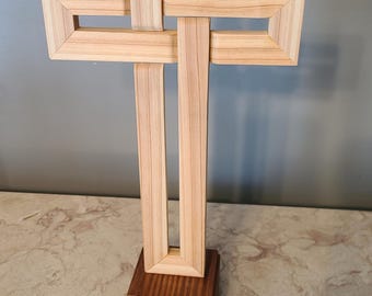 Cruz. Hecha de cedro. Montada sobre un pedestal. Tejida.