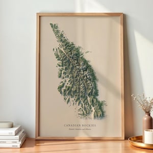 May include: A framed vertical wall art print featuring a topographical map of the Canadian Rockies in shades of green and beige. The text at the bottom reads CANADIAN ROCKIES, British Columbia and Alberta, displayed in a light wood frame.