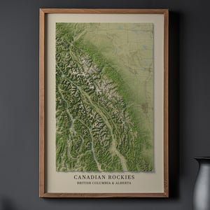 May include: A framed topographic map of the Canadian Rockies in British Columbia and Alberta. The map features shades of green, brown, and white, with the text "CANADIAN ROCKIES" and "BRITISH COLUMBIA & ALBERTA" at the bottom. The frame is a light brown color.