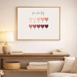 Puede incluir: Impresi&oacute;n enmarcada con las palabras "You Are My Sweet Heart" sobre una serie de corazones en tonos rosas y rojos. La impresi&oacute;n est&aacute; en un marco de madera clara y cuelga de una pared neutra.