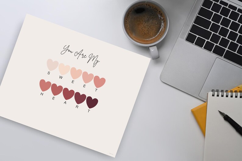 Puede incluir: Una impresi&oacute;n con el texto "You Are My Sweet Heart" sobre una serie de formas de coraz&oacute;n en varios tonos de rosa y rojo. Tambi&eacute;n se ven una taza de caf&eacute;, un port&aacute;til y un bloc de notas.