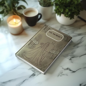 Puede incluir: Una taza de cerámica blanca con un asa negra y el texto "But First, Coffee" en negrita negra. La taza se encuentra sobre un fondo borroso, sugiriendo un ambiente acogedor.