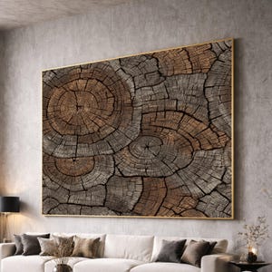 May include: Large framed artwork featuring a close-up of a tree trunk cross-section. The artwork displays concentric circles and cracks in shades of brown and gray, with a gold-colored frame. The piece is a decorative wall hanging.