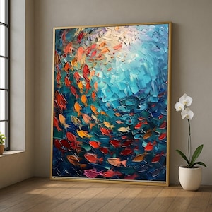 Può includere: Un dipinto astratto di un banco di pesci che nuotano in un oceano blu. I pesci sono di varie tonalità di rosso, arancione e giallo. Il dipinto ha uno stile materico e strutturato ed è incorniciato in una cornice dorata.